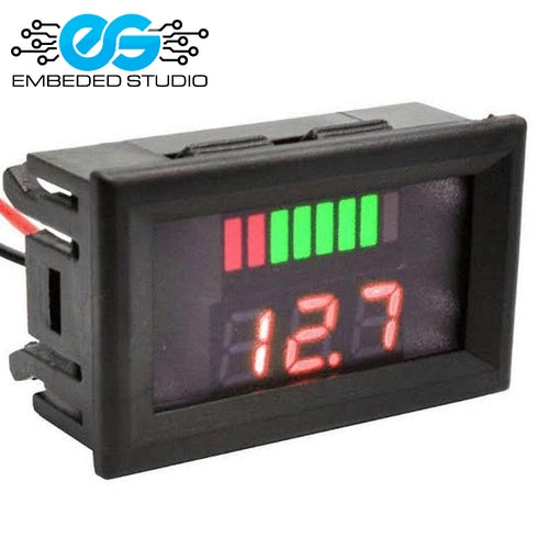 A rectangular black digital battery charge level indicator displaying a red LED readout of "12.7" and a green bar battery graphic, next to the Embeded Studio logo.