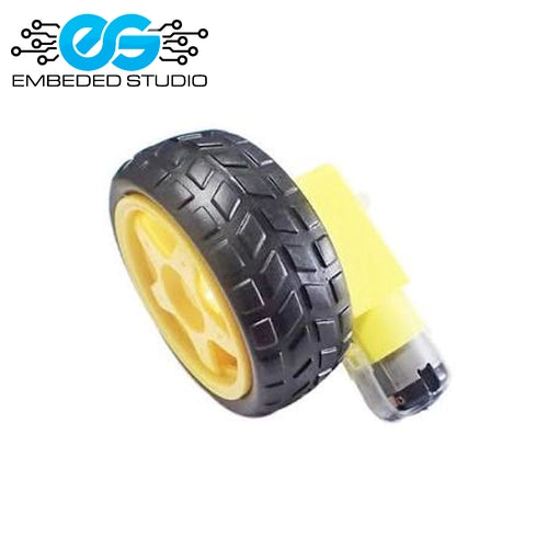 A yellow TT DC gear motor connected to a black rubber tire with a yellow plastic wheel rim, displayed on a white background next to the Embeded Studio logo.