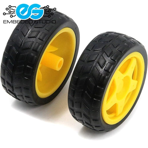 Two black rubber toy car tires with yellow plastic wheel rims, shown from different angles against a white background next to the Embeded Studio logo.
